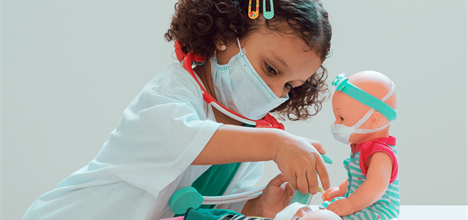 child dressed up as doctor giving dolls a shot